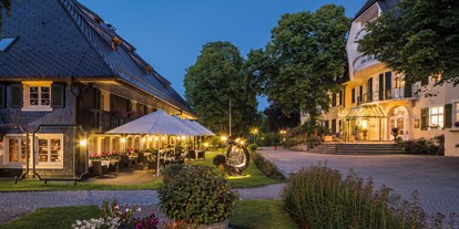 Golfurlaub - veganes Essen - Umkirch - Abendstimmung im Parkhotel Adler mit Restaurantterrasse vor dem historischen Schwarzwaldhaus, das Haupthaus rechts wurde 1890 gebaut. - Parkhotel Adler 